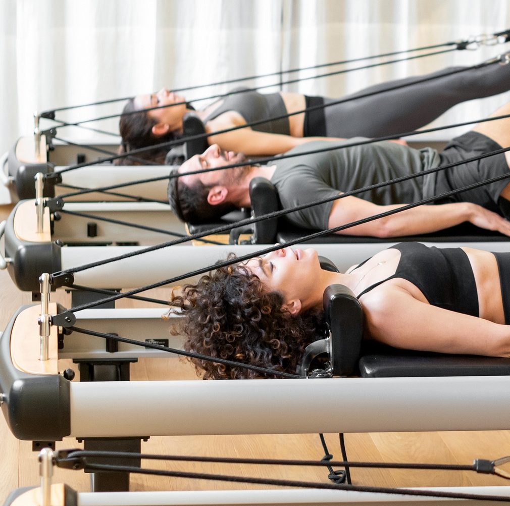 Class of diverse people doing the hundred pilates exercise on reformer beds in a gym in a healthy active lifestyle concept